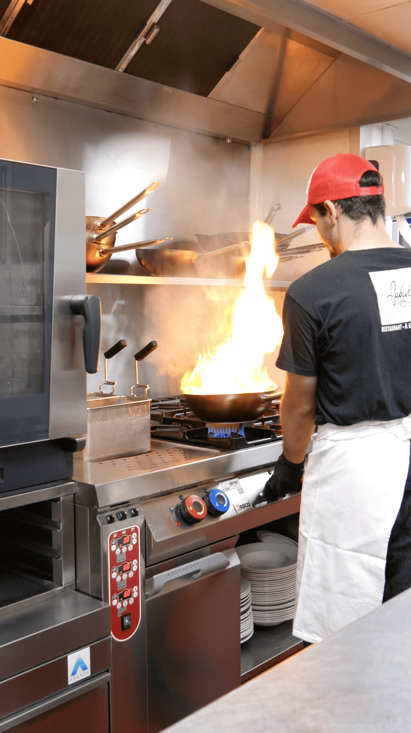 Cuisinier Fabioli faisant flamber une poêle dans la cuisine du restaurant