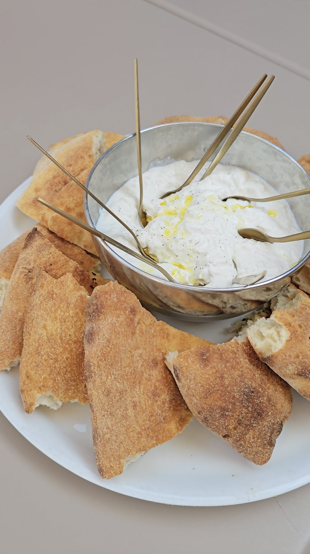 Bol de burrata crémeuse arrosée d'huile d'olive et de poivre, entourée de tranches de pizza bianca, à partager chez Fabioli