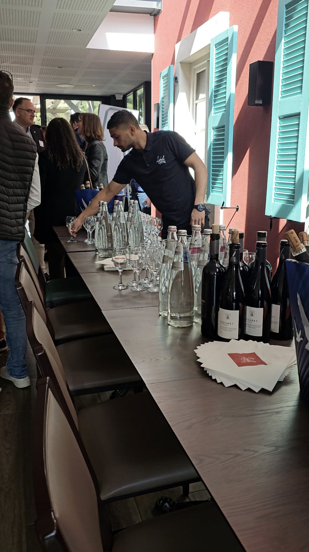 Serveur Fabioli dressant la grande table d'un événement privé, verres, eaux et vins de Séguret alignés