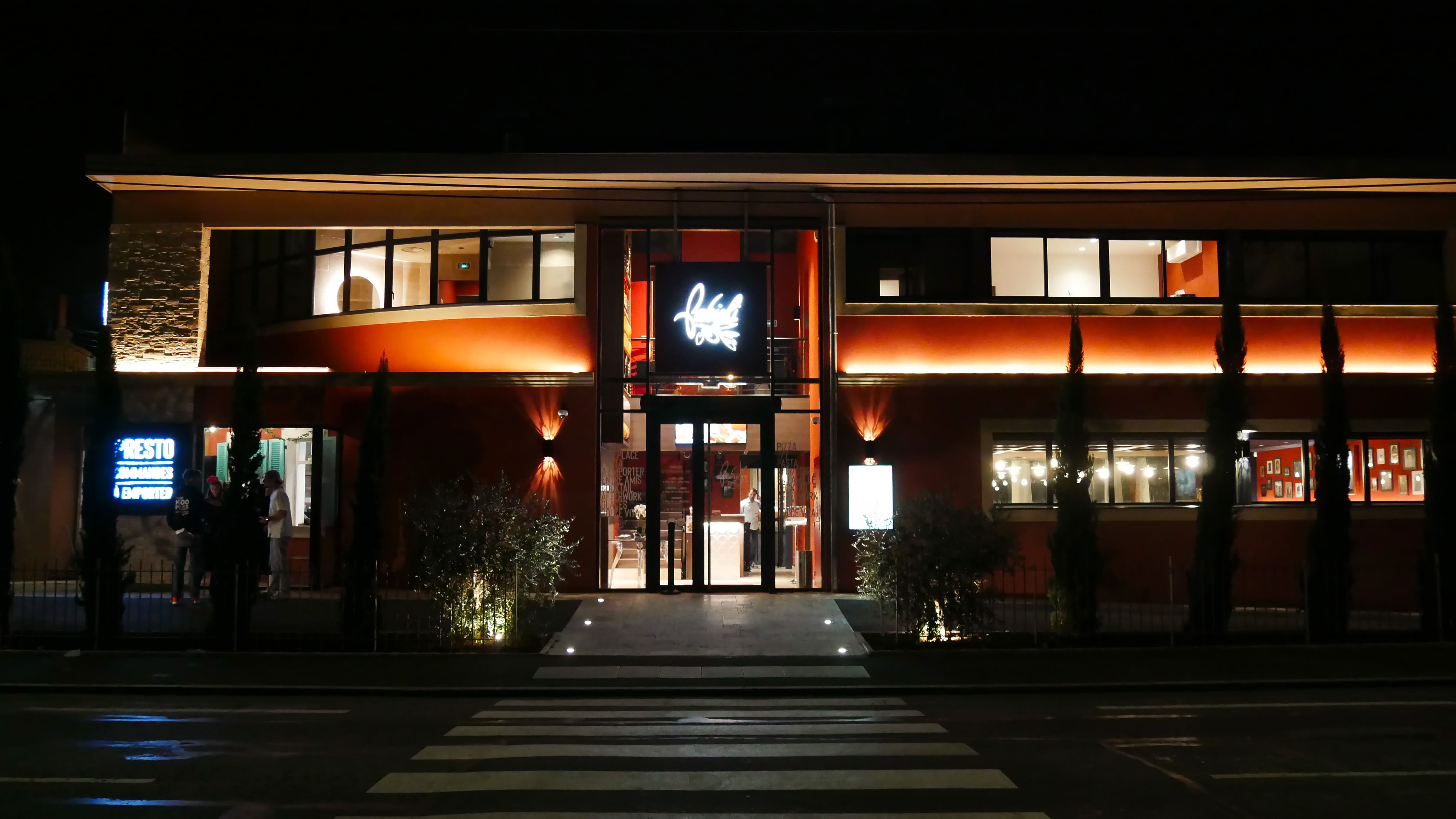Façade illuminée d'un restaurant Fabioli à la tombée de la nuit, enseigne au néon