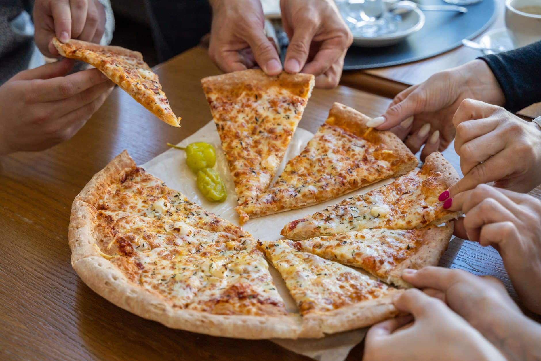 Mains qui se servent des parts de pizza autour d'une table familiale au restaurant