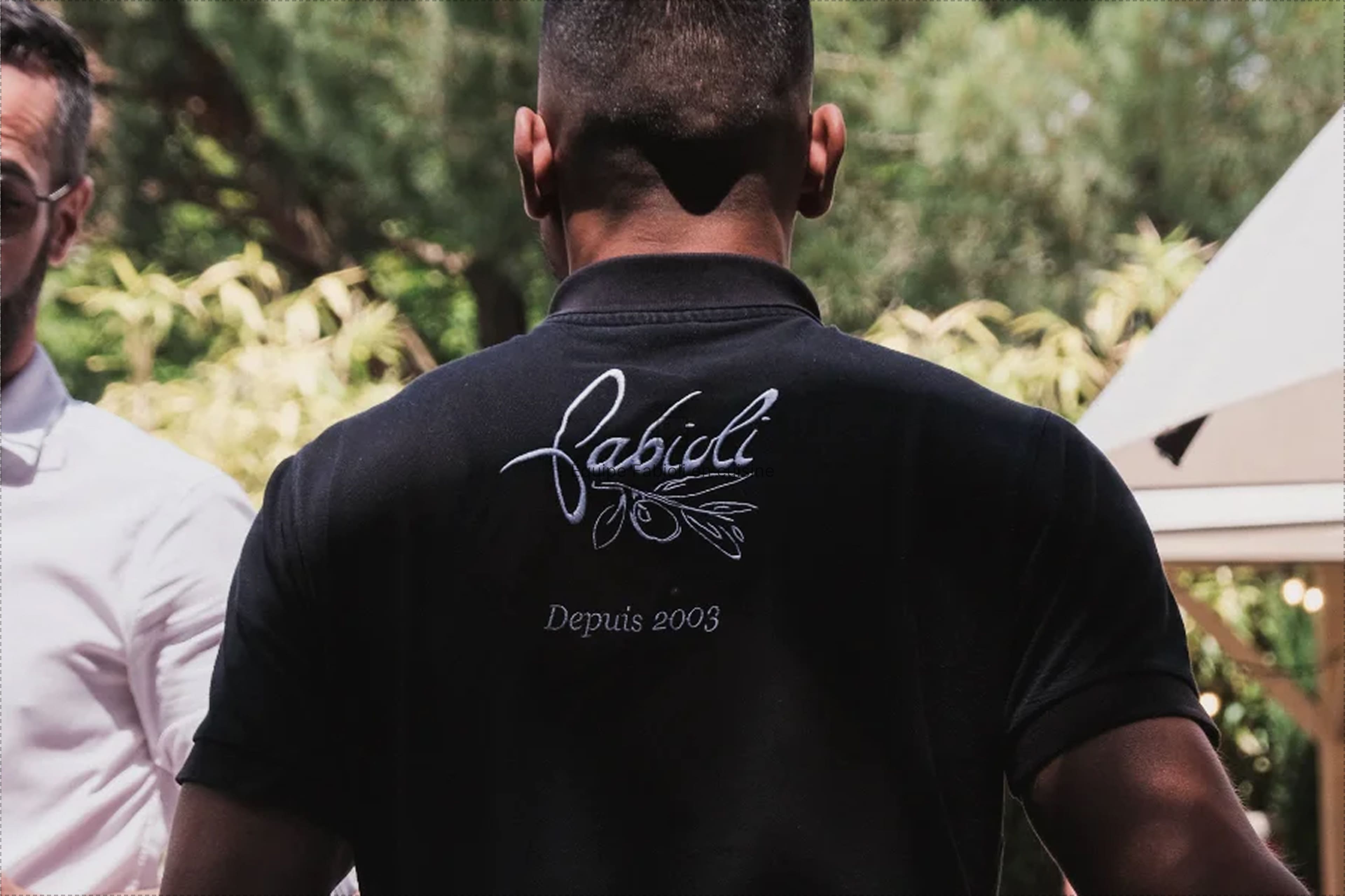 Serveur Fabioli de dos portant le polo brodé de la signature Fabioli et sa branche d'olivier, depuis 2003