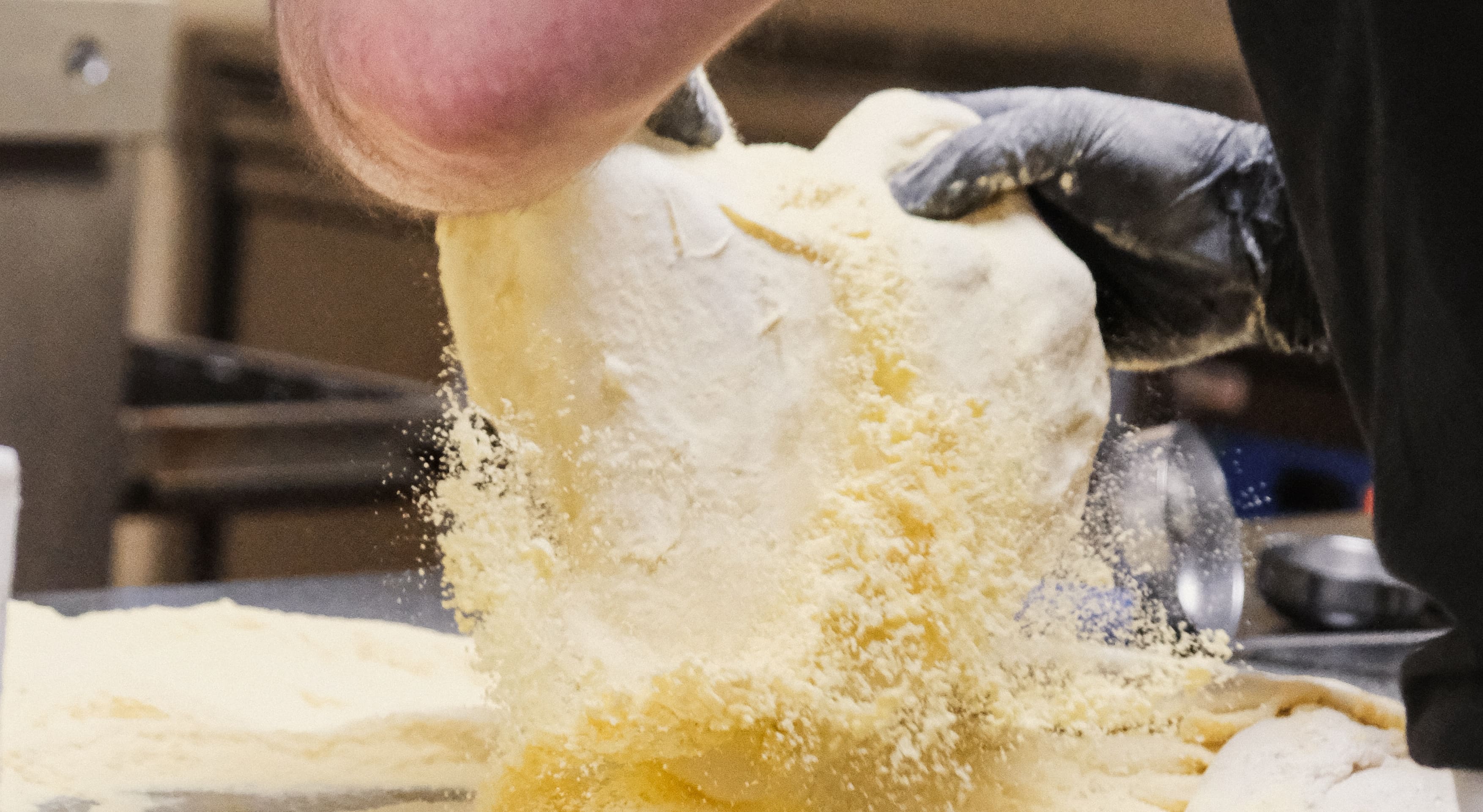 Pizzaïolo Fabioli travaillant à la main la pâte à pizza farinée dans le laboratoire