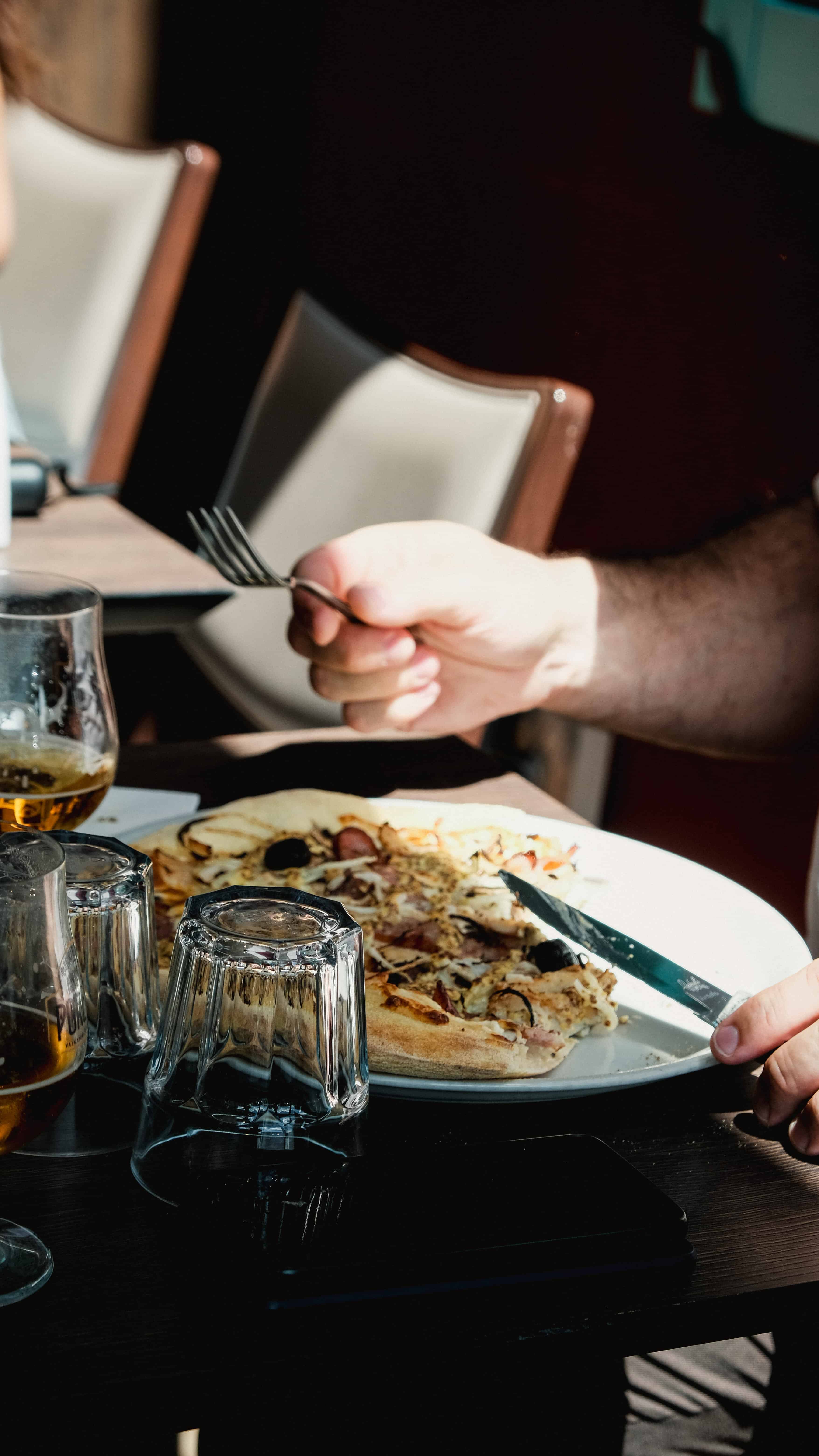 Convive dégustant une pizza chez Fabioli, verre de bière et lumière du soir